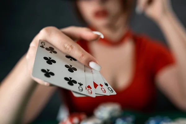 poker player sits at a poker table with cards in her hands and poker chips on the table. poker. casino