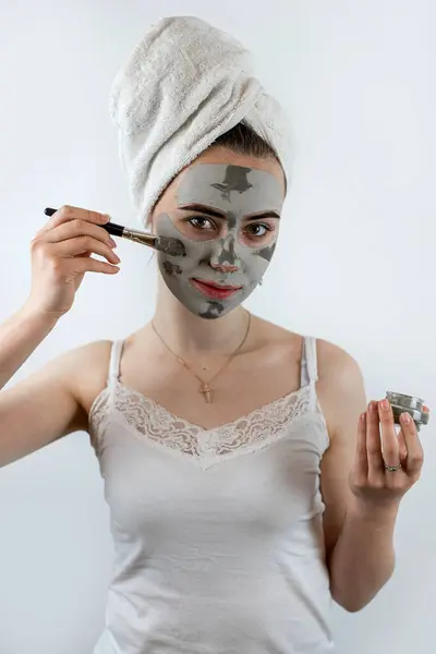 caucasian woman applying clay mask with brush on her face, skin care, moisturizer. Healthcare concept