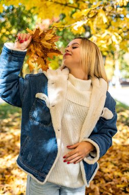 Güzel, mutlu bir gülümseme genç bir kadın sonbahar ormanında günlük giysiler giyer. Oldukça neşeli mutlu kız modeli..