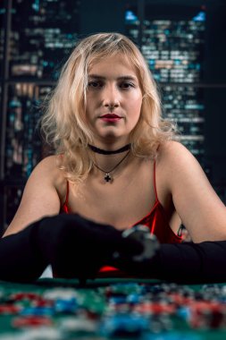 Kırmızı elbiseli ve şapkalı güzel kız poker oynuyor. Duygusuz bir yüz. Kumar.