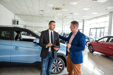 Müşteri araba galerisinde profesyonel bir erkek yöneticiye yardım ederek modern bir araba alıyor. Başarı anlaşması kavramı