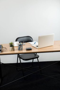 Ahşap ofis masasında bir kalem dizüstü bilgisayar. Ev konseptinde serbest çalışma