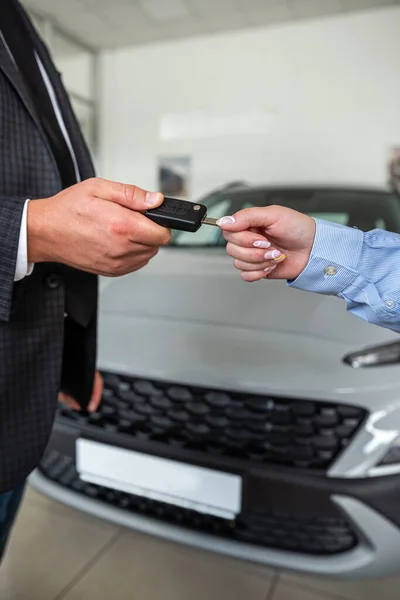 salesman give car key customer after success deal at modern showroom. close up. sale concept