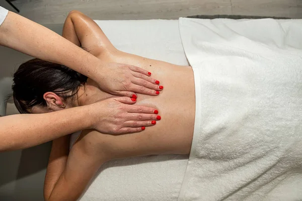 Pretty slim caucasian woman receiving relax massage treatment by professional therapist is spa clinic. Body care concept