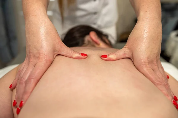 Pretty slim caucasian woman receiving relax massage treatment by professional therapist is spa clinic. Body care concept