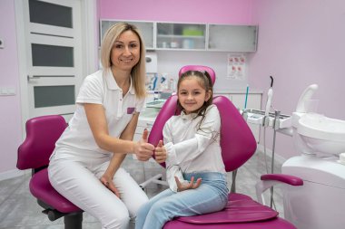 children's dentist conducts a consultation for a little girl in a dental chair. children's dentistry. the doctor talks about the importance of oral care