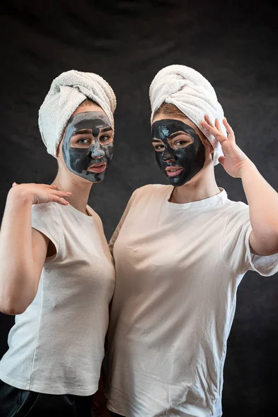 Friends female people make mud clay mask as anti aging treatment isolated on black. Spa wellness. Stay beautiful, healthcare grooming