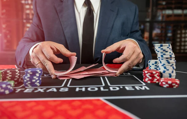 Man croupier holding playing cards before start game poker at casino. Texas holdem, gambling concept