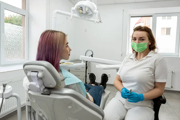 Portrait of a happy female patient sitting in a dental chair next to a young female dentist doctor who is conducting an examination. dentistry.