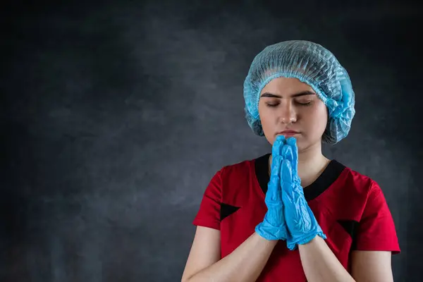 medical woman doctor or nurse with hands clasped in prayer isolated on black. Hope concept