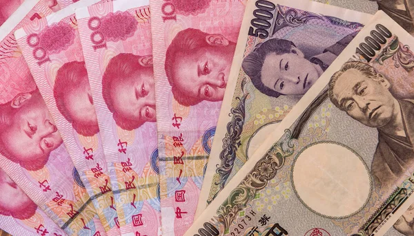 Asian money - Chinese yuan with Japanese yen bill, finance background