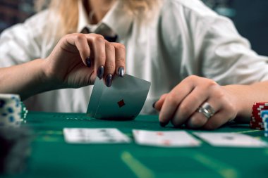 Kumarhanede elinde poker kartları tutan tişörtlü ve şapkalı çekici bir kız. poker. bayan oyuncu