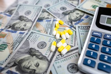  Üzerinde reçeteli haplar olan hesap makinesi. Amerikan dolarları. Tıbbi ya da eczane masrafları. Eczacılık teması