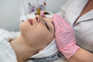 Kaplıcada yaşlanmayı önleyen yüz masajı yaptıran genç ve güzel bir kadın. Deri bakımı konsepti. Yaşlanma önleme prosedürü 