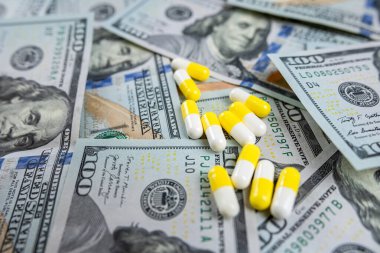 Farklı renklerde ilaç hapları içeren Amerikan kağıt paraları. Reçeteli ilaç, dövüş fiyatı.