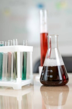 Masasında farklı renkte sıvılar olan deney laboratuarı mataraları. Tıbbi ve kimyasal deneyler kavramı