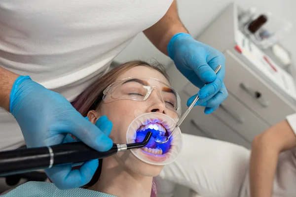 male and female dentists use a UV lamp to harden the patient\'s fillings. dentistry teeth