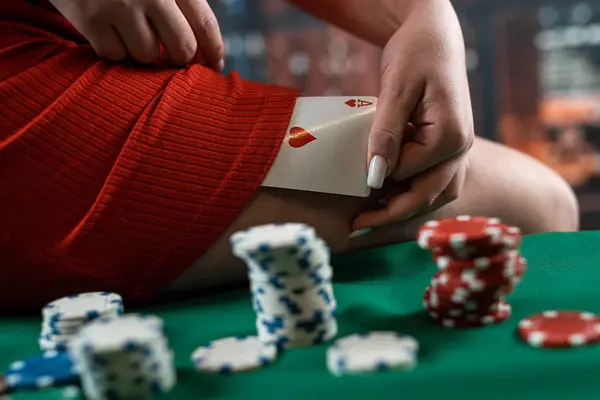 young woman in a casino in a red dress sits on a poker table with chips and cards. Poker. seductive woman