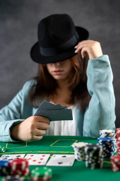 beautiful girl came to the night casino to play poker at a wide green table. a woman in a hat. poker game excitement. big money