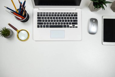 Ofis beyaz masasında laptoplu tablet kalem faresi ve kreatif işler için klavye var. İşyeri