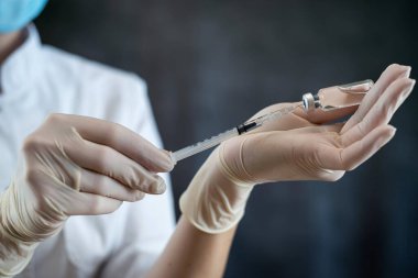 Tam üniformalı beyaz kadın hemşire ya da bilim adamı izole edilmiş insanlar için şırınga aşısı hazırlıyor. Grip veya koronavirüs aşısı