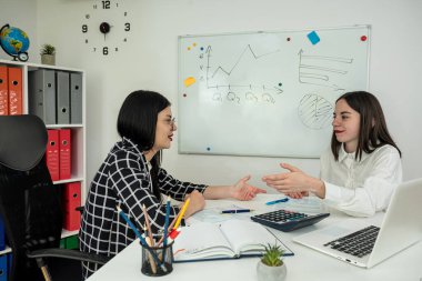 İki genç iş kadını konuşuyor ve 1040 vergi formunu dolduruyor. Vergi zamanı. Yıllık rapor