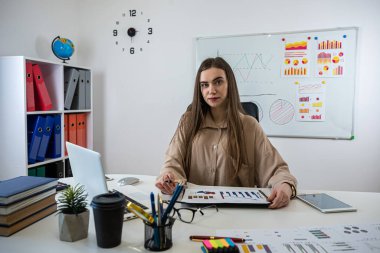 İş kadını ofiste çalışıyor. Belgeler, grafikler ve mali raporlarla. İşyeri