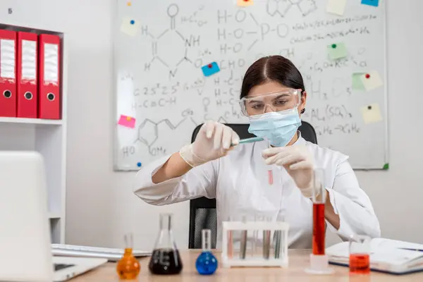 Young woman laboratory technician mixed flask with liquid, research in clinical laboratory. Medicaments testing