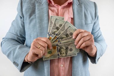 Genç iş adamı, elindeki dolarları gri ve finans sayısına izole ederek gösteriyor.