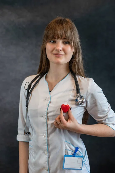 Female nurse in uniform with the stethoscope holding small red heart. We care concepts.