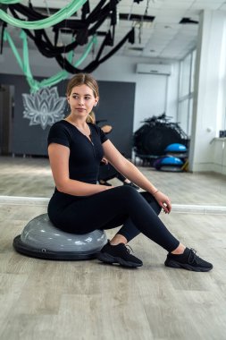 Genç sporcu kadın figürü sıkılaştırmak için dengeleyici bir minder üzerinde egzersiz yapıyor. Spor konsepti. pilates