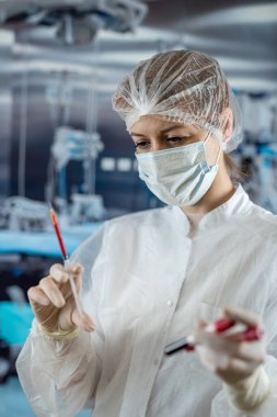 nurse in labcoat mask and gloves holds syringe with blood in surgery. Blood tests and analysis at lab