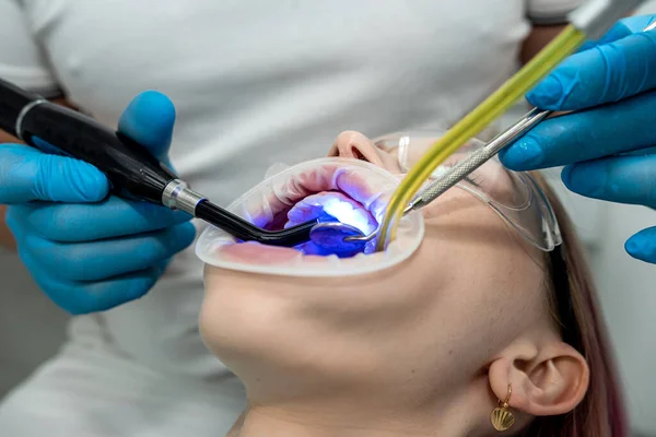 male and female dentists use a UV lamp to harden the patient\'s fillings. dentistry teeth