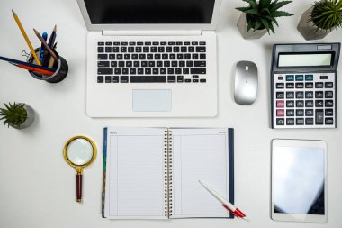 Ofis beyaz masasında laptoplu tablet kalem faresi ve kreatif işler için klavye var. İşyeri
