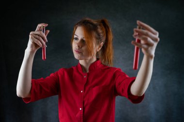 Kırmızı üniformalı doktor test tüpündeki kanı inceliyor, salgına karşı koruma sağlıyor. Sağlık çalışanı