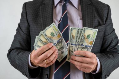 Elinde para banknotları tutan adam gri arka planda. Finans yatırım kavramı