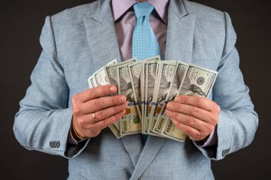 İş adamı takım elbise giyer ve bize siyah üzerine izole edilmiş dolar para banknotlarını gösterir. Finans kavramı