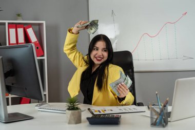 İş kadını maaş ya da vergi için dolar banknotları sayıyor, dizüstü bilgisayar kullanıyor ve ofiste mali belgeler çiziyor. Harcama kavramı