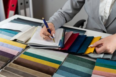 Kadın tasarımcı, evdeki yeni mobilyalar için en parlak rengi doku örneklerinden seçiyor. Kumaş örnekleyici