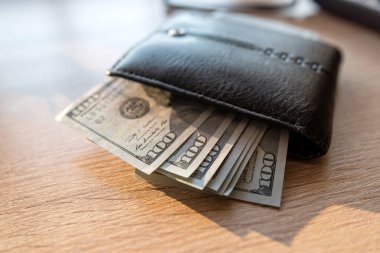 Ofis masasında dolar banknotları olan siyah deri bir cüzdan. Finans kavramı