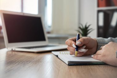 Not defterine dizüstü bilgisayarla not alan kadın elini kapat, ofiste çalış ya da evde serbest çalış. Uzaklık çevrimiçi çalışma kavramı