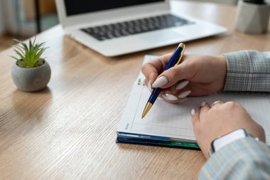 Not defterine dizüstü bilgisayarla not alan kadın elini kapat, ofiste çalış ya da evde serbest çalış. Uzaklık çevrimiçi çalışma kavramı