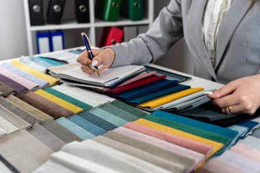 Kadın tasarımcı, evdeki yeni mobilyalar için en parlak rengi doku örneklerinden seçiyor. Kumaş örnekleyici