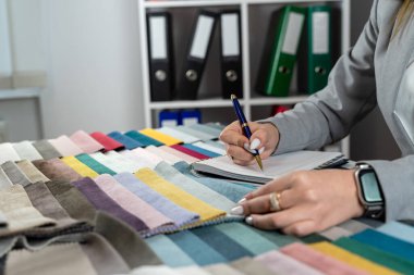Kadın tasarımcı, evdeki yeni mobilyalar için en parlak rengi doku örneklerinden seçiyor. Kumaş örnekleyici