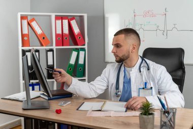 Modern klinikte masasında tek başına çalışan beyaz önlüklü ve steteskoplu doktor doktor portresi. Uzaklık hekimi kavramı