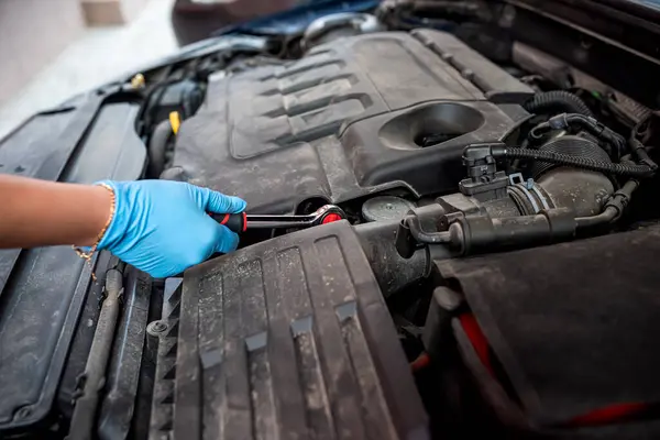 car mechanic repairs a car engine near a car with an open hood. car maintenance. repair services.