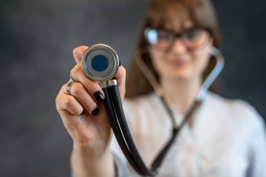 Beyaz üniformalı, steteskoplu, karanlıkta izole bir kadın hemşire ya da stajyer. Kliniğe hoş geldin, sağlık çalışanı.