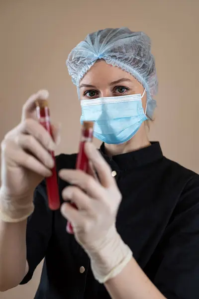 Caucasian woman scientist in black uniform holding sample blood test tube, diagnostic labs