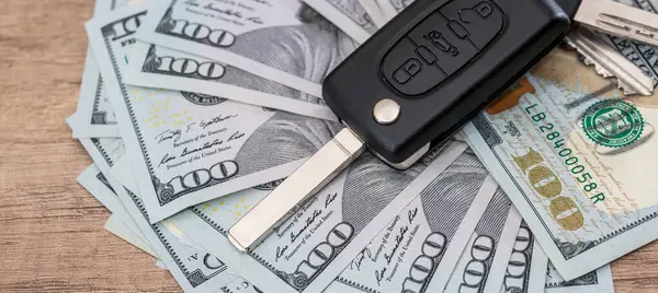 black car key on dollar paper money on desk. Buy or rent a car