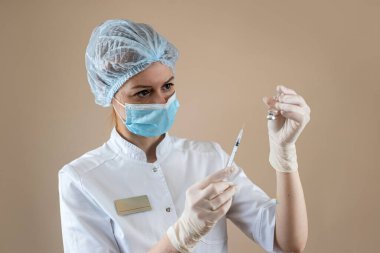 Beyaz üniformalı genç bir hemşire, şırınga ve sıvı aşı tutan eldivenler. Tıbbi bakım kavramı